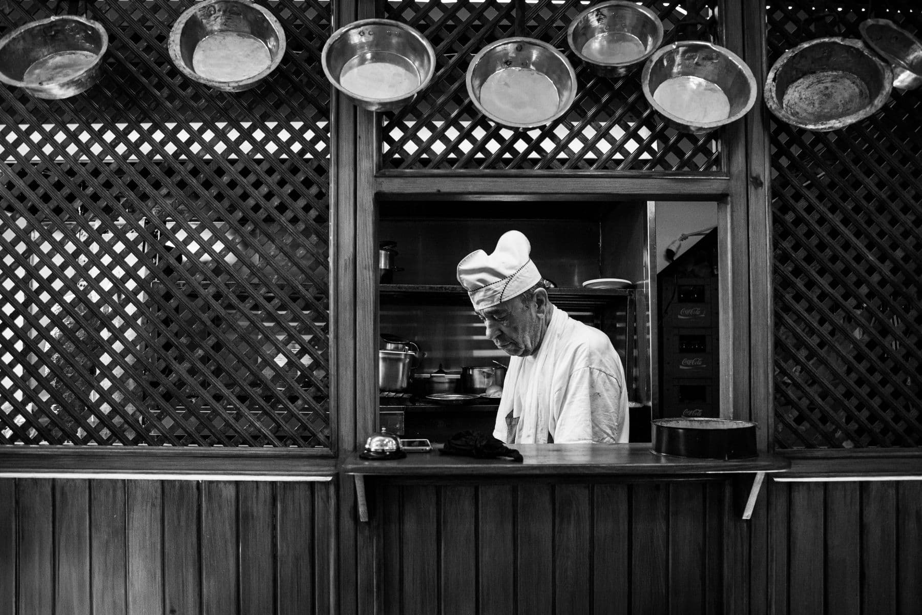 Black and white photograph of a cook framed in the service window
