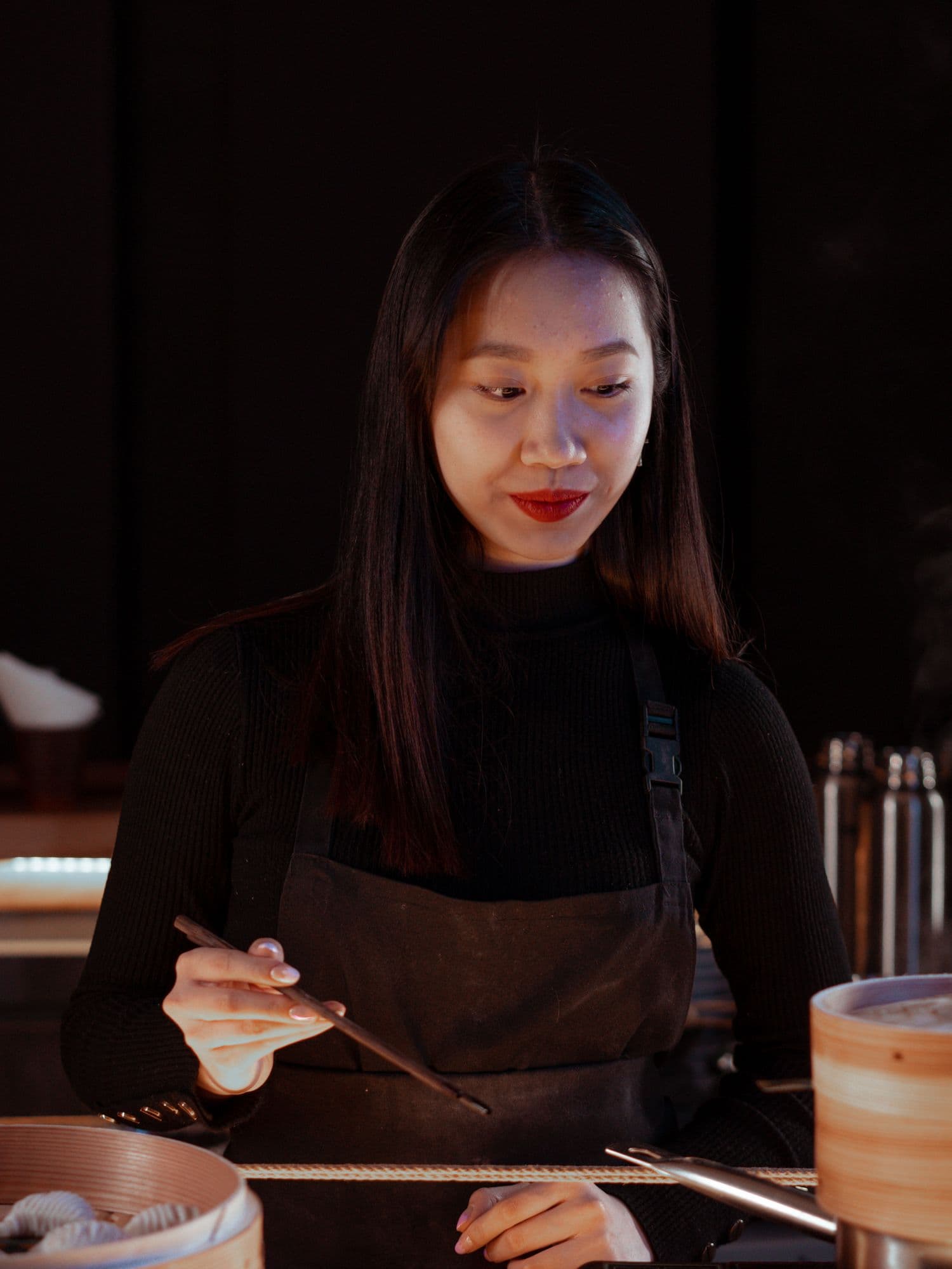 Ariana Krasniqi in a dark apron, plating at the pass