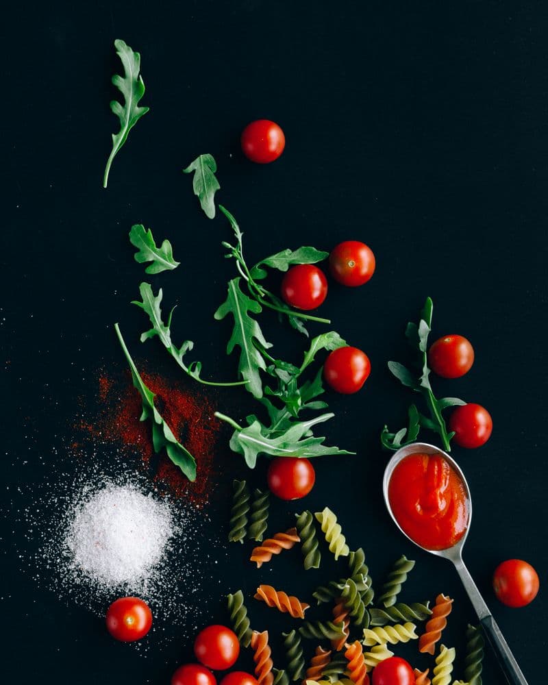 Raw market vegetables, cherry tomatoes and arugula scattered on slate