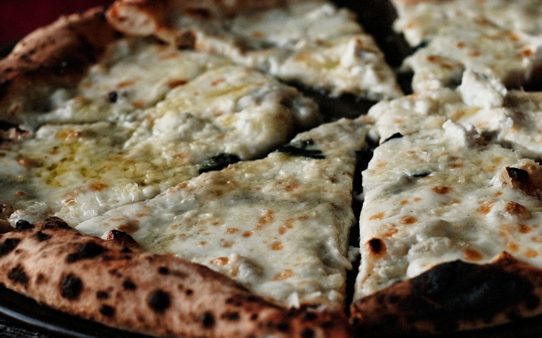 A white pizza cut into six slices, crust blistered and charred