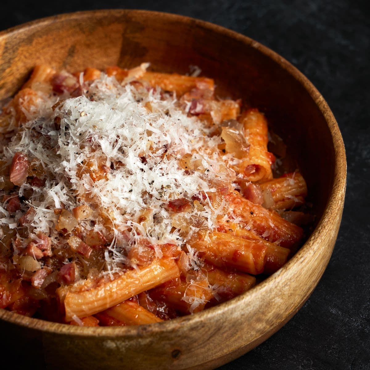 Close crop of rigatoni buried under grated pecorino