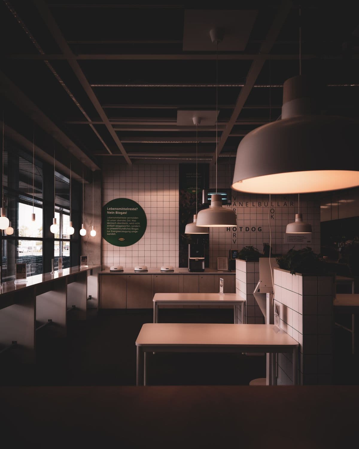 Looking down the length of the room, pendants over bare tables
